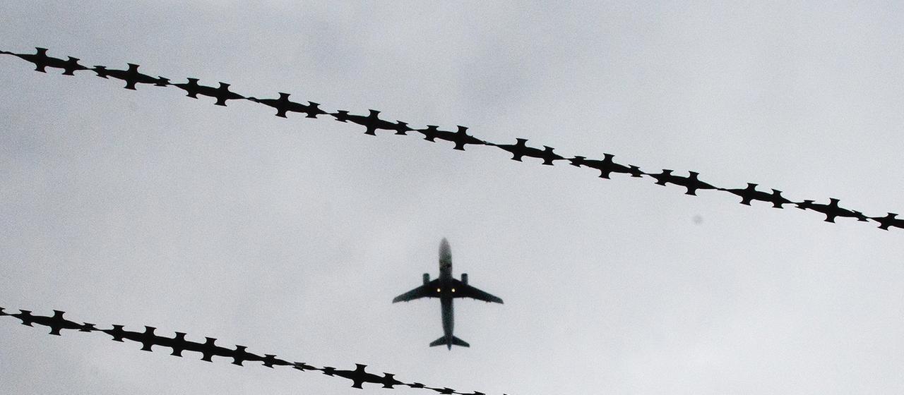 Ein Flugzeug ist hinter Stacheldraht zu sehen.