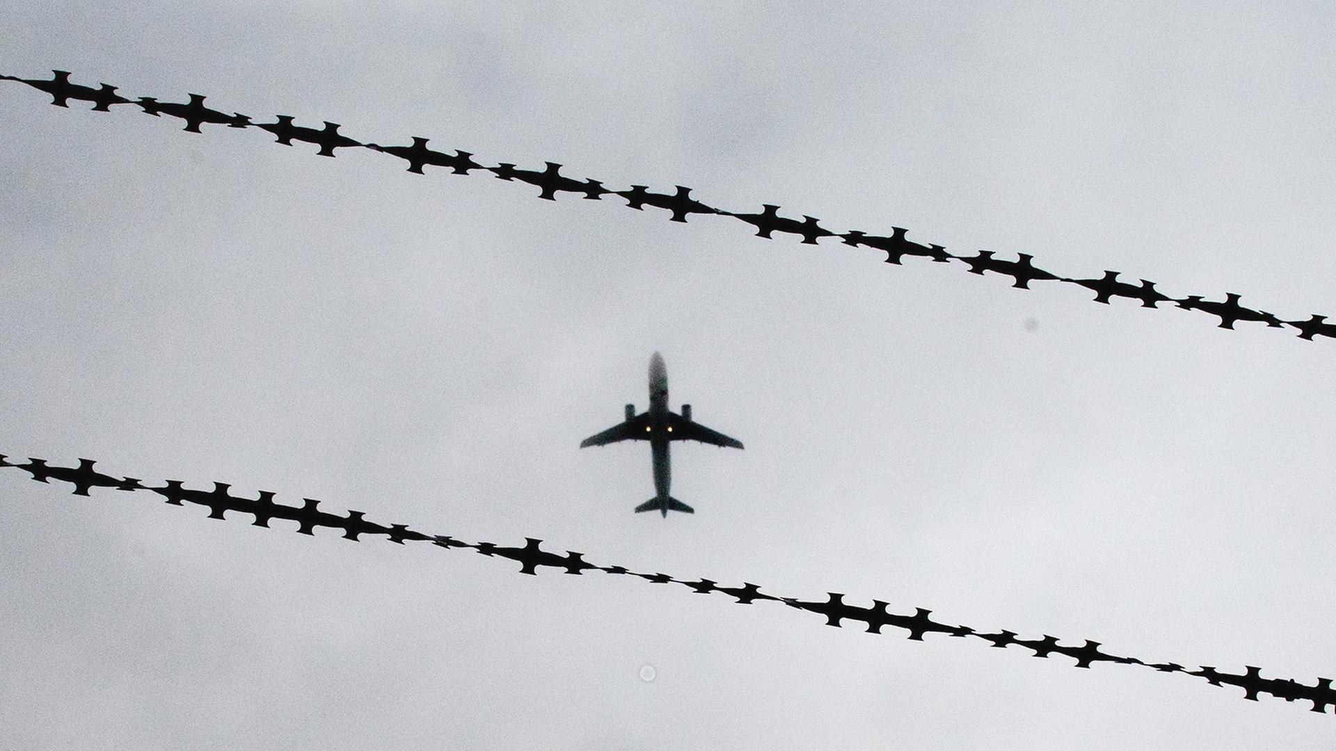 Ein Flugzeug ist hinter Stacheldraht zu sehen. | dpa