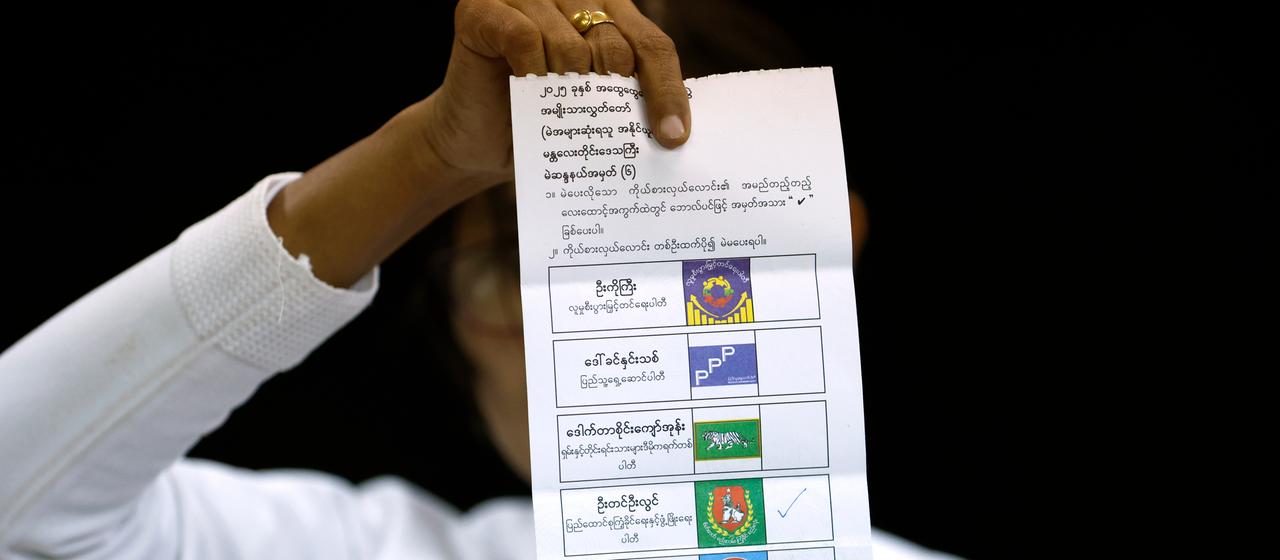 Eine Wahlhelferin hält einen Stimmzettel in die Höhe