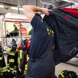 Symbolbild: Ein Feuerwehrmann zieht sich während der Vorstellung zur Bilanz von Feuerwehr und Rettungsdienst Potsdam für einen Einsatz an. (Quelle: dpa/Gollnow)