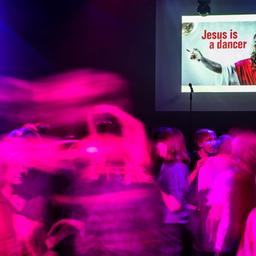 Während auf einer digitalen Anzeige der Spruch "Jesus is a dancer" aufleuchtet, tanzen Menschen trotz des Tanzverbots an Karfreitag in einem Club.