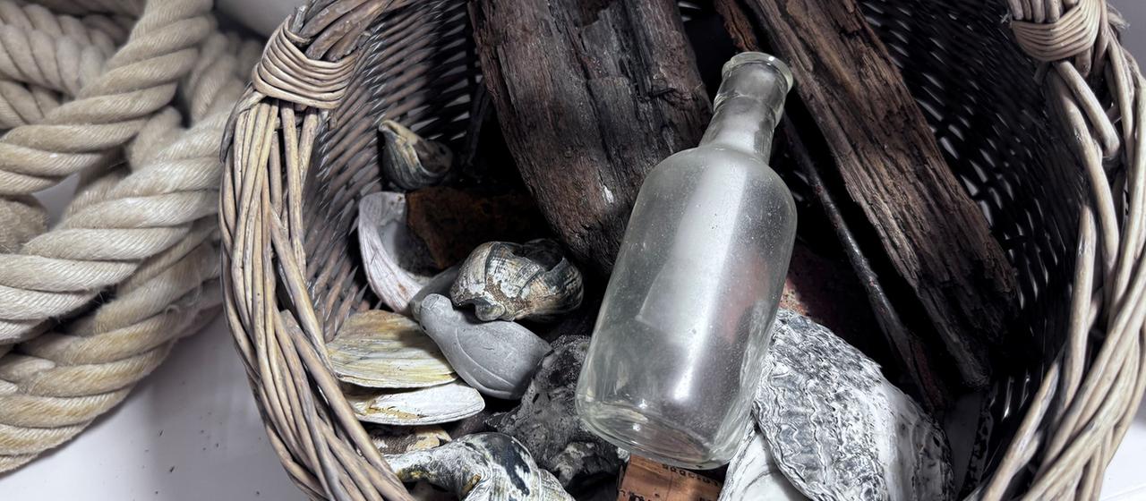 Eine Flaschenpost liegt in einem Korb.