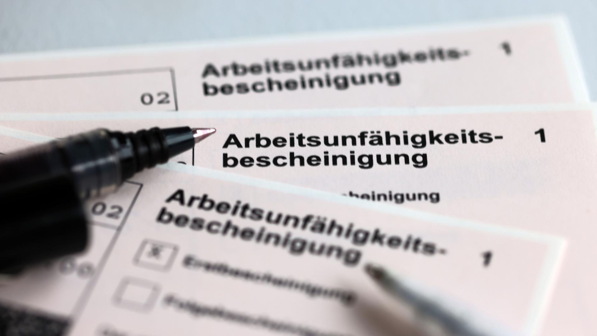 Kugelschreiber liegen auf Arbeitsunfähigkeitsbescheinigungen | dpa-tmn