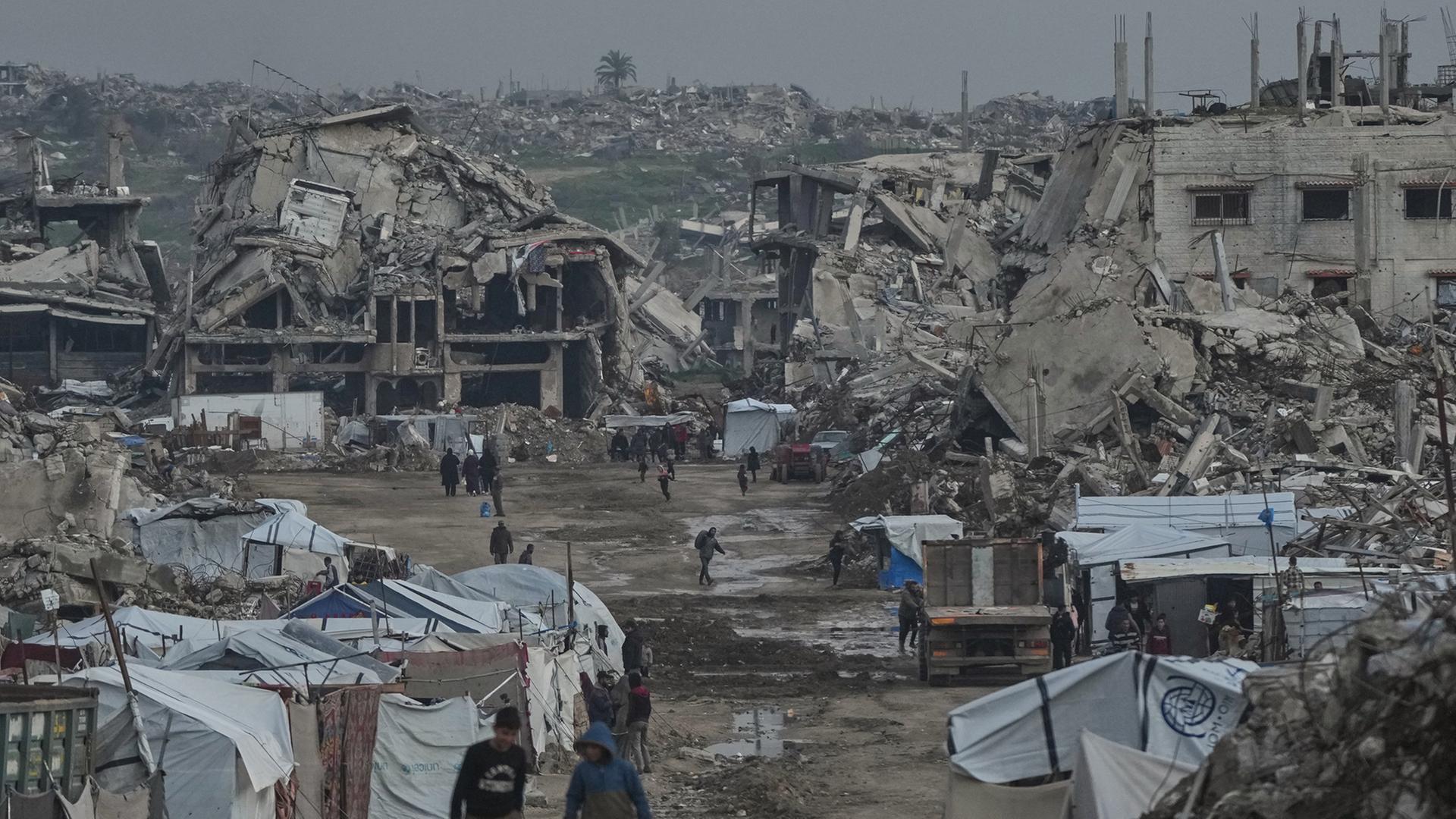 Palästinenser gehen zwischen zerstörten Gebäuden im Stadtteil Zeitoun in Gaza-Stadt. | AP