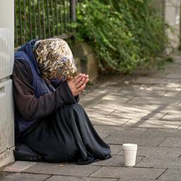 Eine ältere Frau beim Betteln am Straßenrand in München.