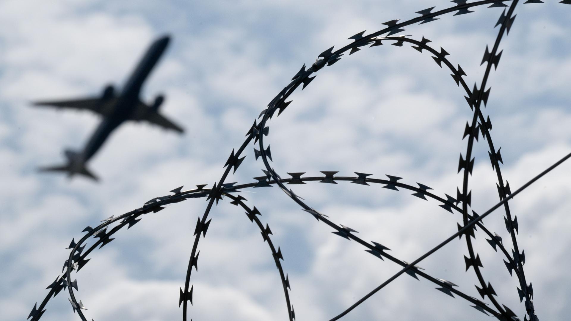 Ein Flugzeug am Himmel, davor Stacheldraht | Sebastian Gollnow/dpa