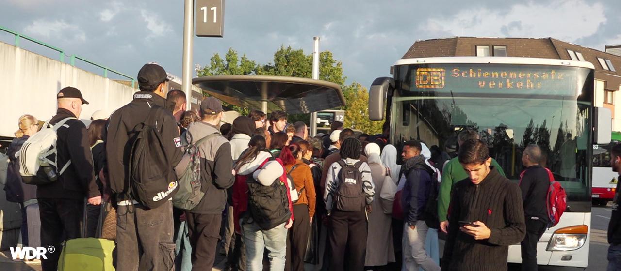 An einer Bushaltestelle am Gelsenkirchener Hauptbahnhof drängen sich viele Menschen, um in einen Bus des Schienenersatzverkehrs zu kommen
