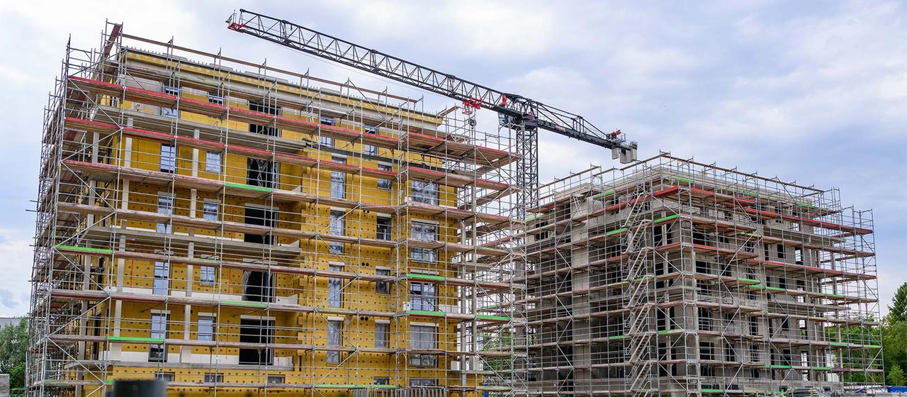 Auf einer Baustelle entstehen Mehrfamilienhäuser mit vielen Wohneinheiten.