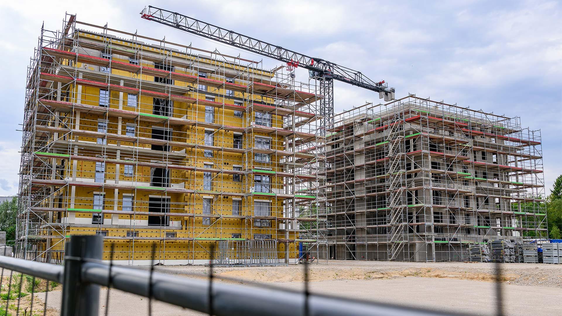 Auf einer Baustelle entstehen Mehrfamilienhäuser mit vielen Wohneinheiten. | picture alliance/dpa