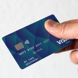 Ein Geflüchteter hält eine Debitcard in der Hand.