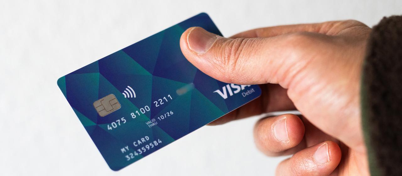 Ein Mann hält eine Debitcard in der Hand.