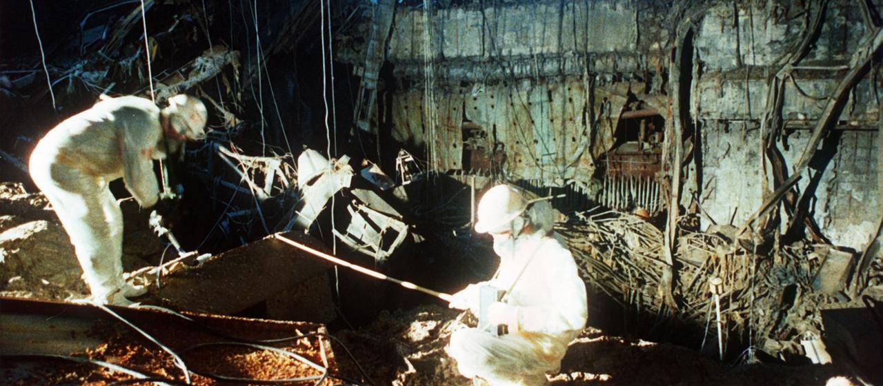 Zwei Männer arbeiten im zerstörten Reaktorblock.