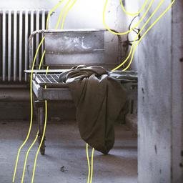 Ein leeres, kaputtes Bett mit einer dünnen Decke in einem verlassenen Krankenhaus.