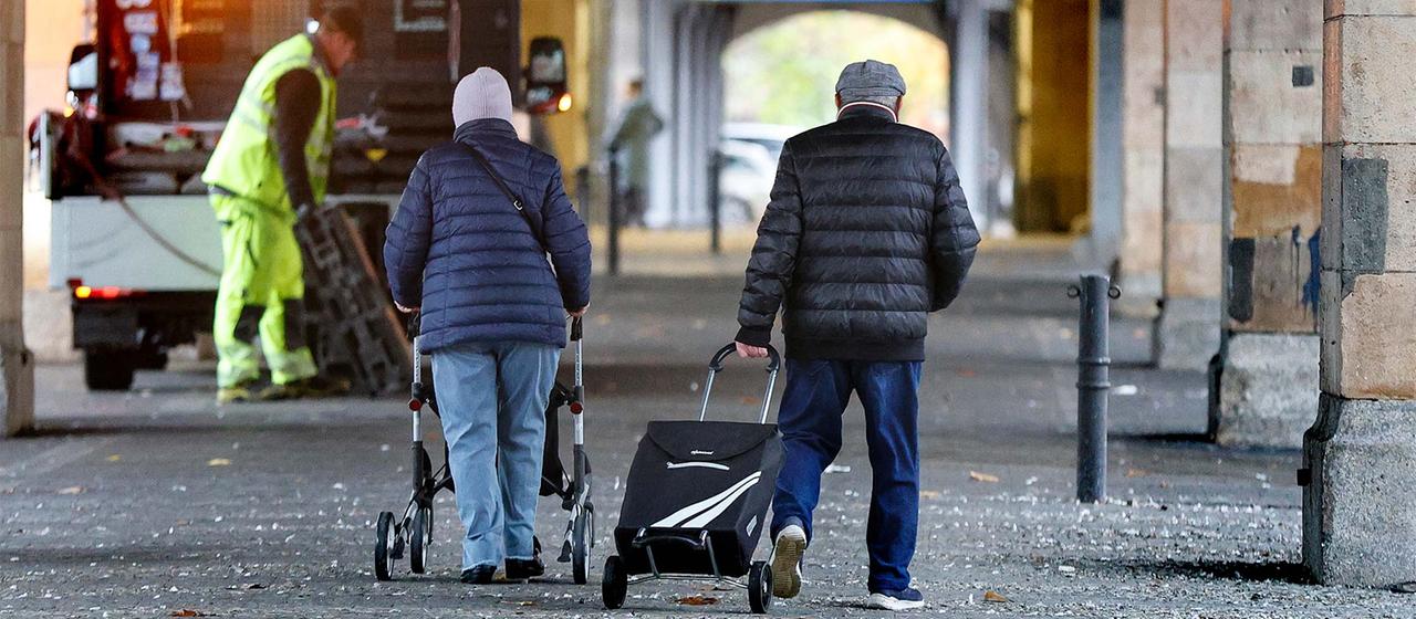 Rentnerpaar mit Rollator und Einkaufswagen.