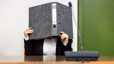  Eine Angeklagte, die sich der Terrormiliz Islamischer Staat (IS) im Irak angeschlossen haben soll, hält sich im Gerichtssaal einen Aktenordner vor das Gesicht.