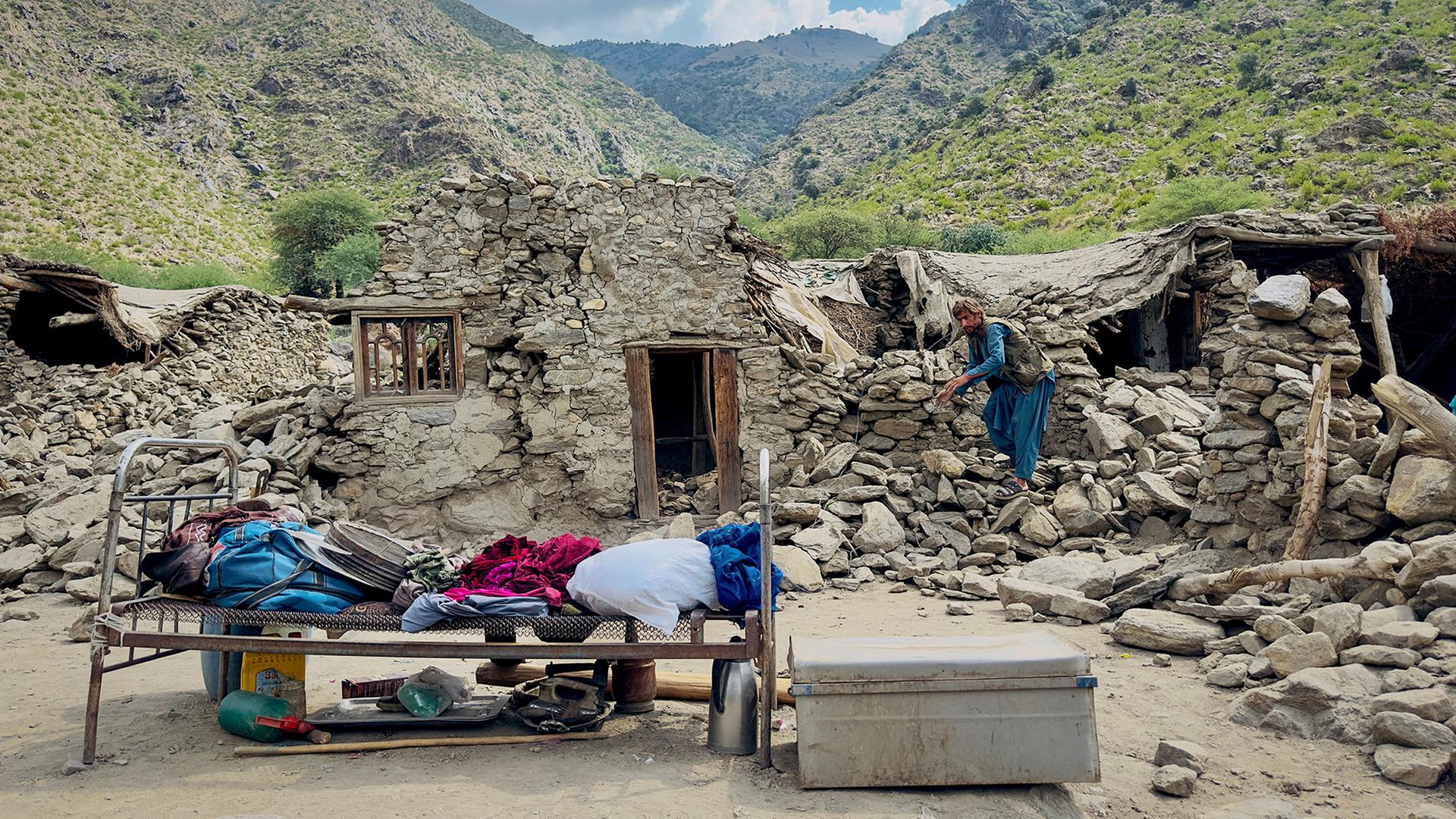 Ein Mann steht in den Trümmern eines Hauses im Dorf Lulam im Bezirk Nurgal (Afghanistan). | REUTERS