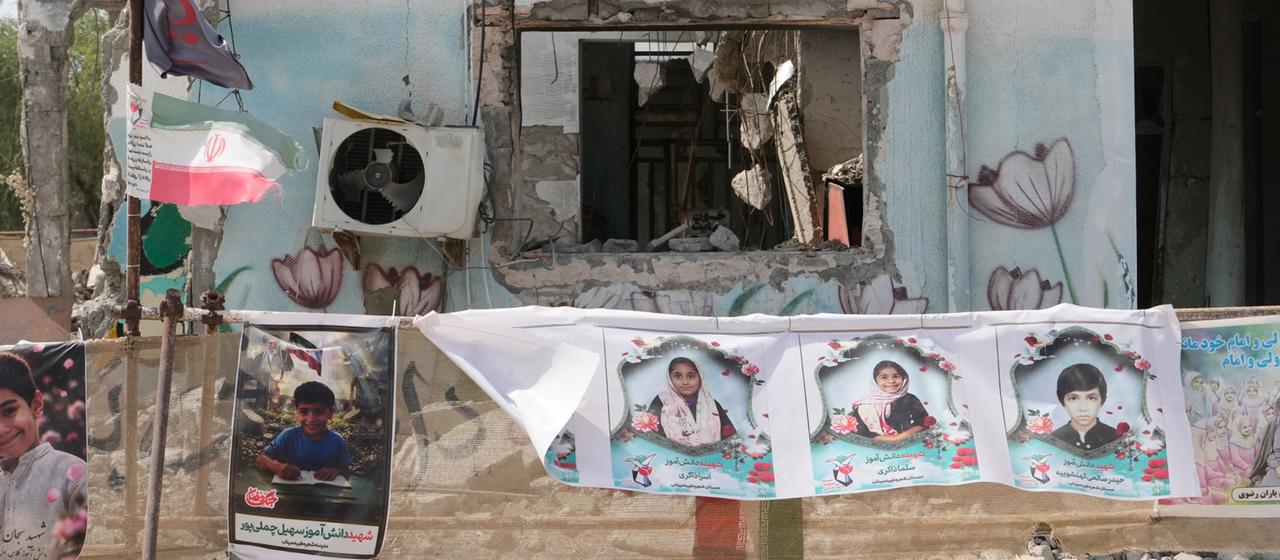 Vor der zerstörten Schule im iranischen Minab hängen Plakate von verstorbenen Kindern.