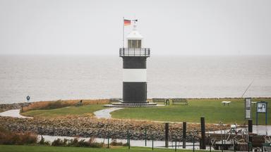 Der Leuchtturm "Kleiner Preusse" steht unter einem grauen, regnerischen Himmel.