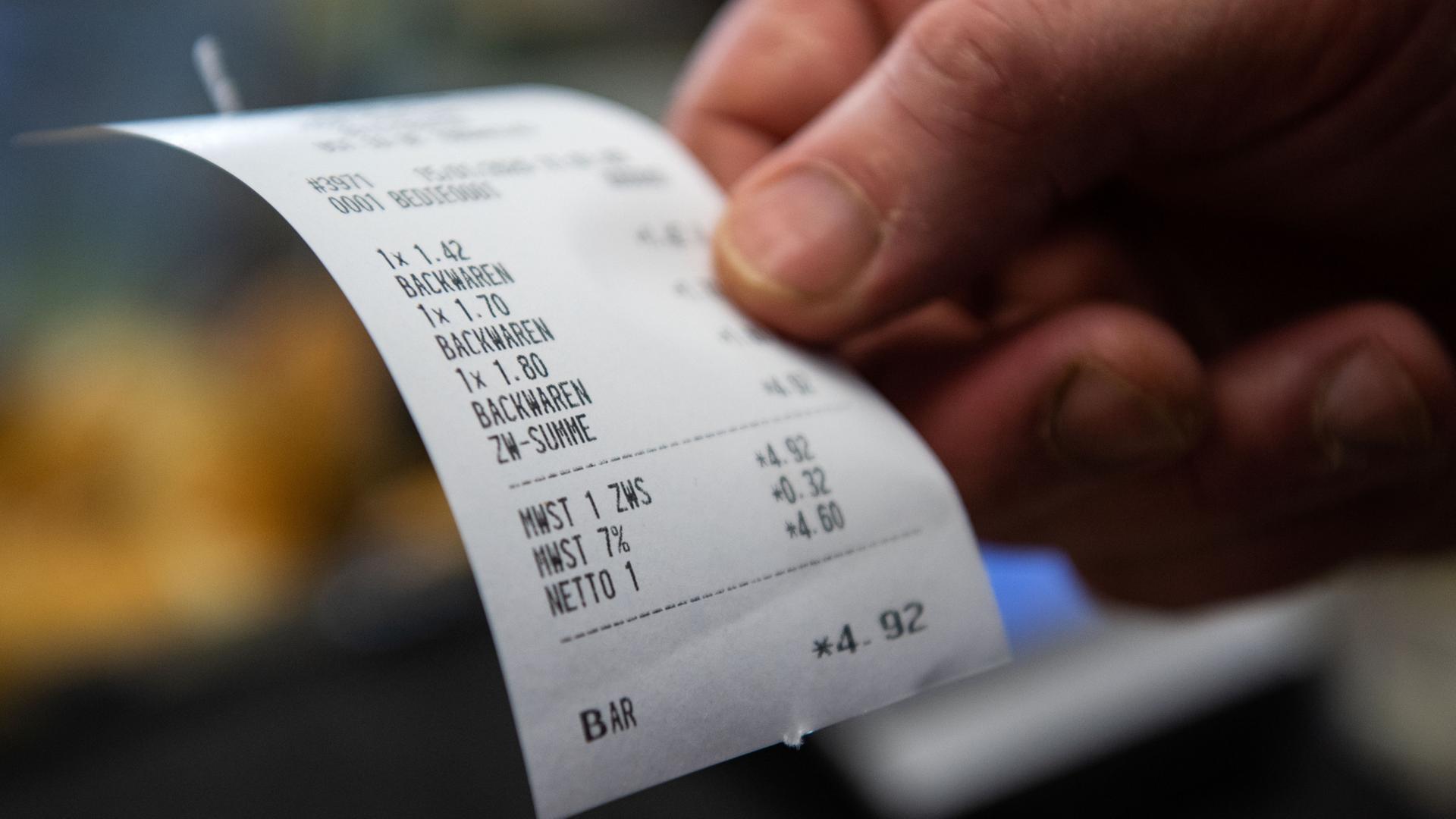 Ein Bäcker hält in seiner Bäckerei einen Bon in der Hand. | dpa