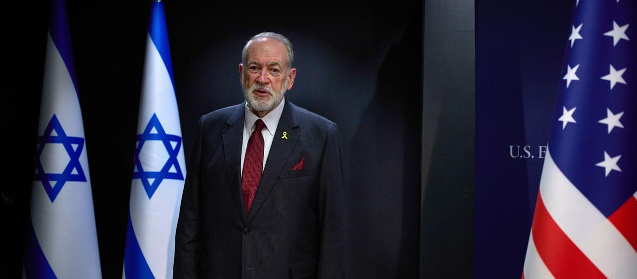 Mike Huckabee auf einer Bühne, umrahmt von einer israelischen und einer US-Flagge.