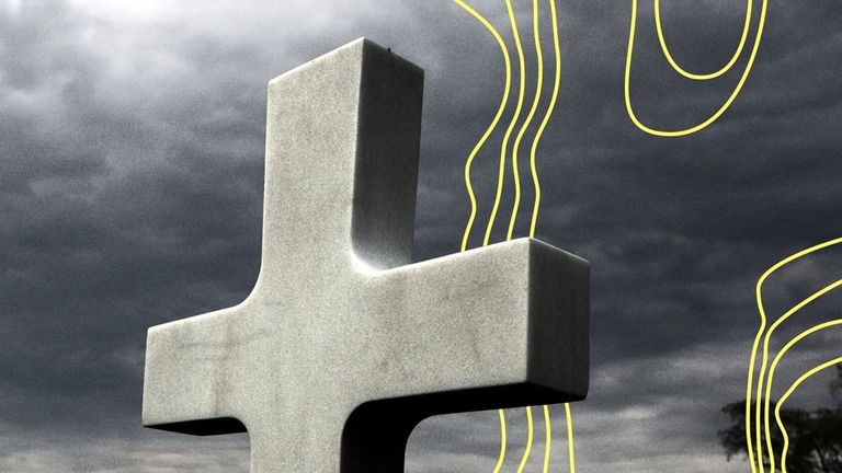 Ein großes Steinkreuz vor einem dunklen, bewölkten Himmel.