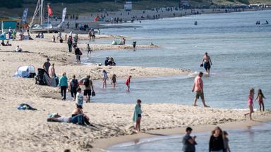 Feriengäste spazieren entlang des Ostseestrandes in Zinnowitz, Mecklenburg-Vorpommern.