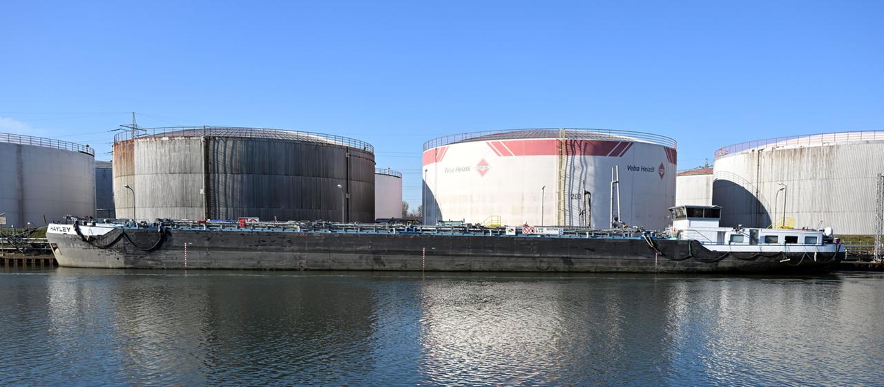 Ein Tankschiff liegt vor Öltanks am Rhein-Herne-Kanal.
