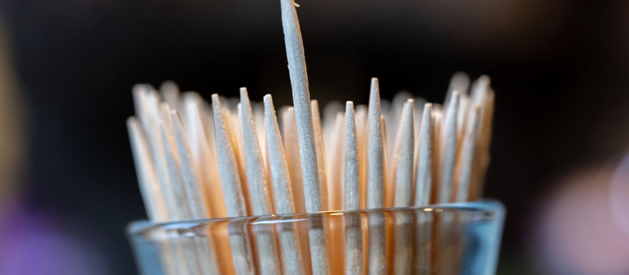 Zahlreiche Zahnstocher stehen in einem Glas. 