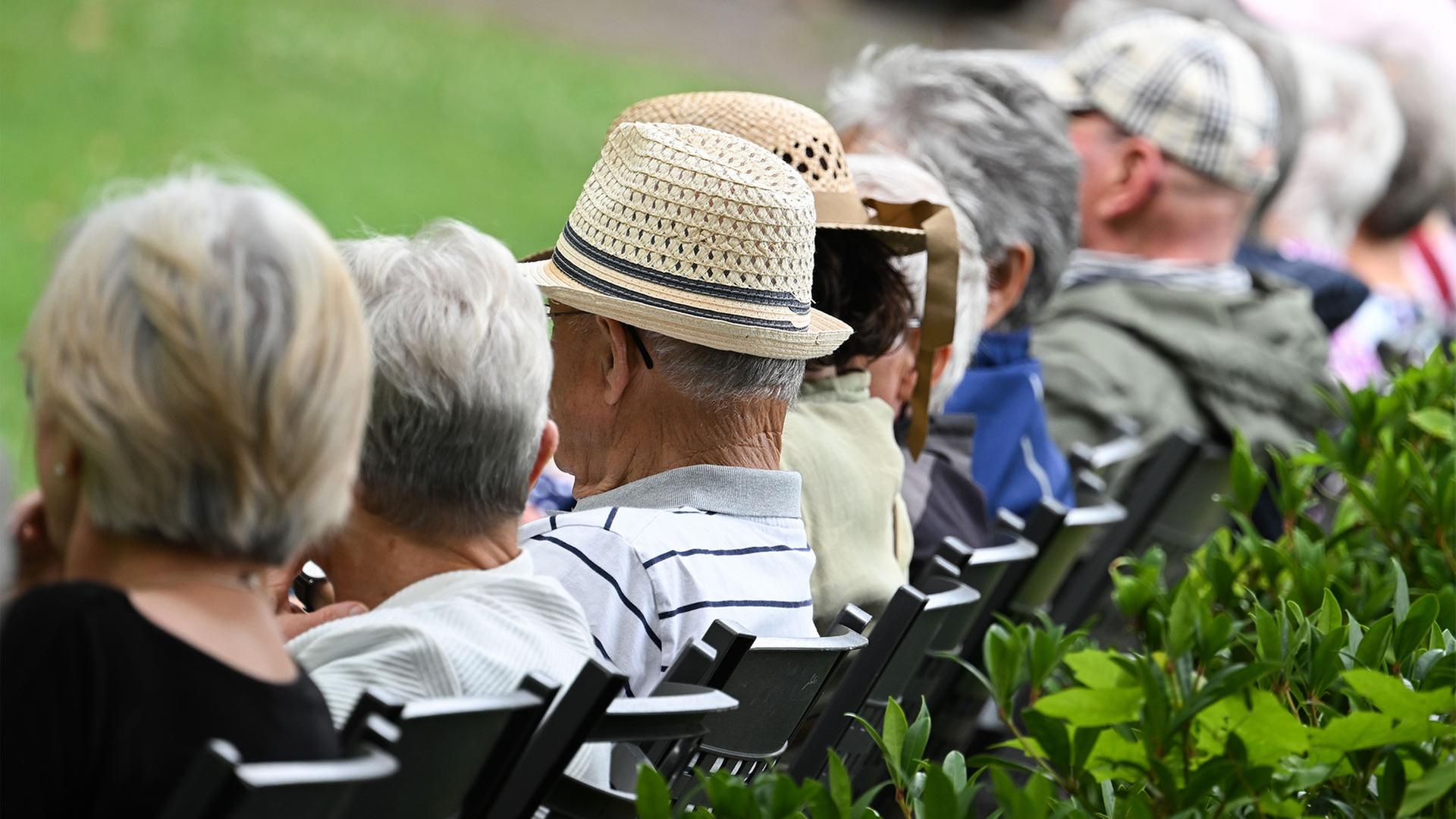 Ältere Menschen sitzen in einem Kurpark. | picture alliance/dpa