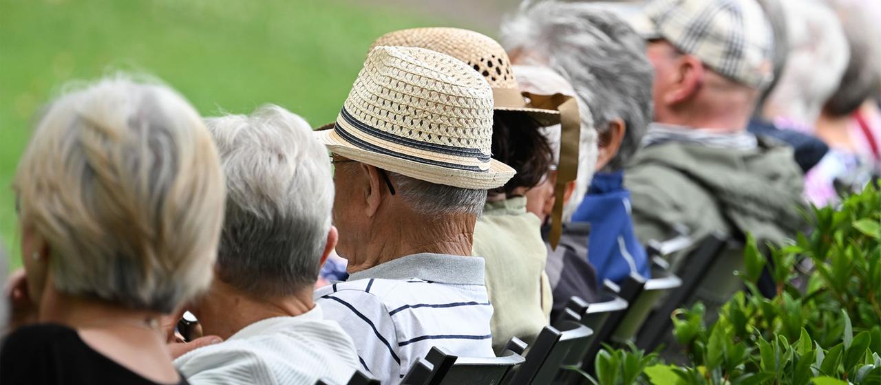 Ältere Menschen sitzen in einem Kurpark.