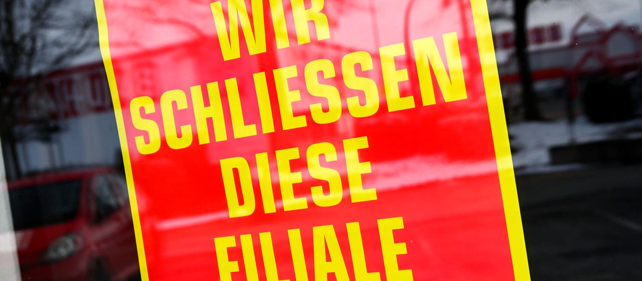 Schild mit Aufschrift "Wir schließen diese Filiale" in einem Schaufenster