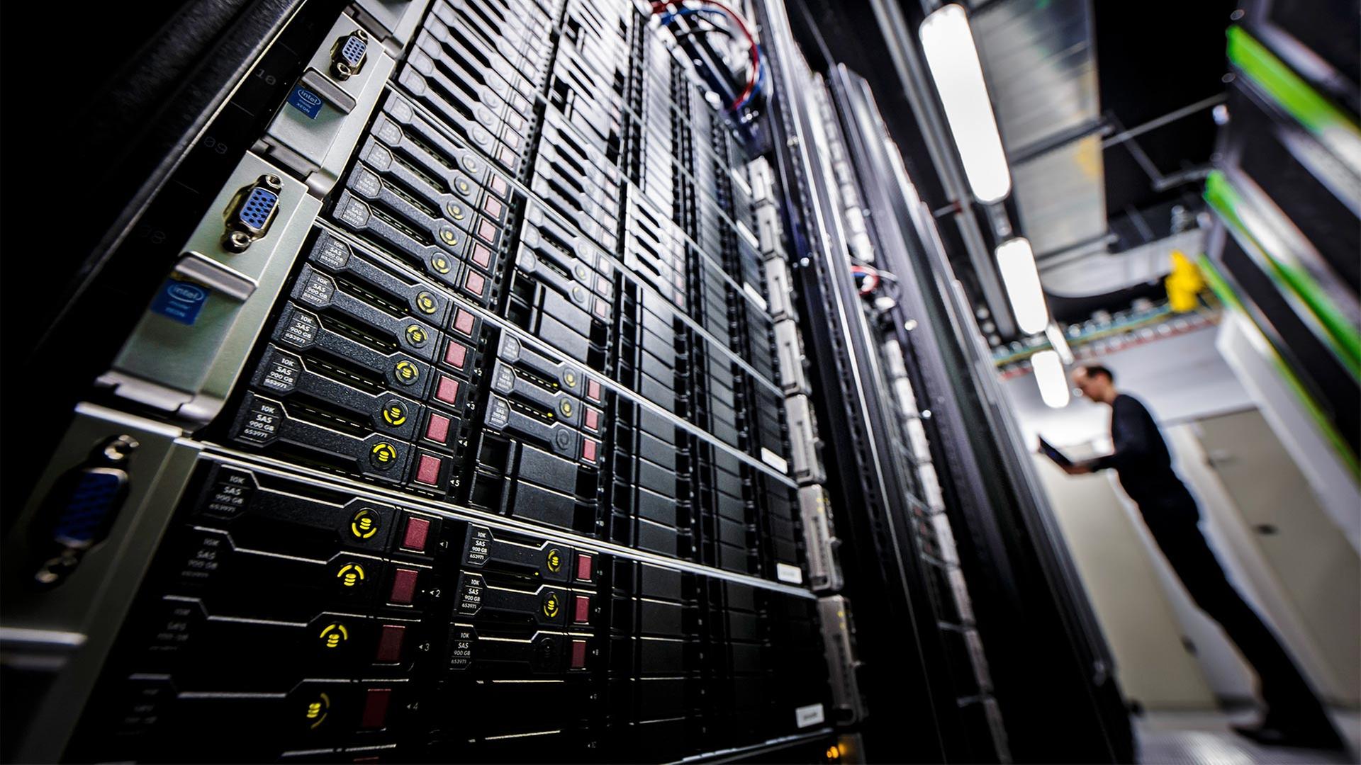 Ein Mann in einem Rechenzentrum neben Serverschränken. | picture alliance / photothek