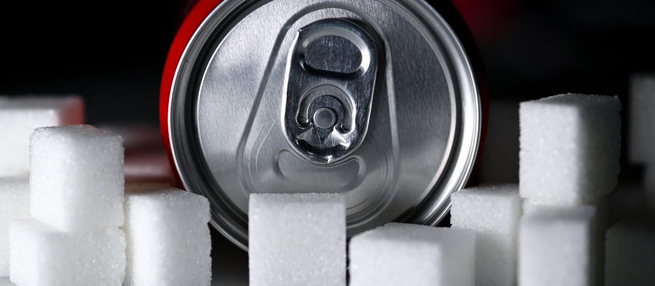 Eine Getränkedose liegt zwischen Zuckerwürfeln.