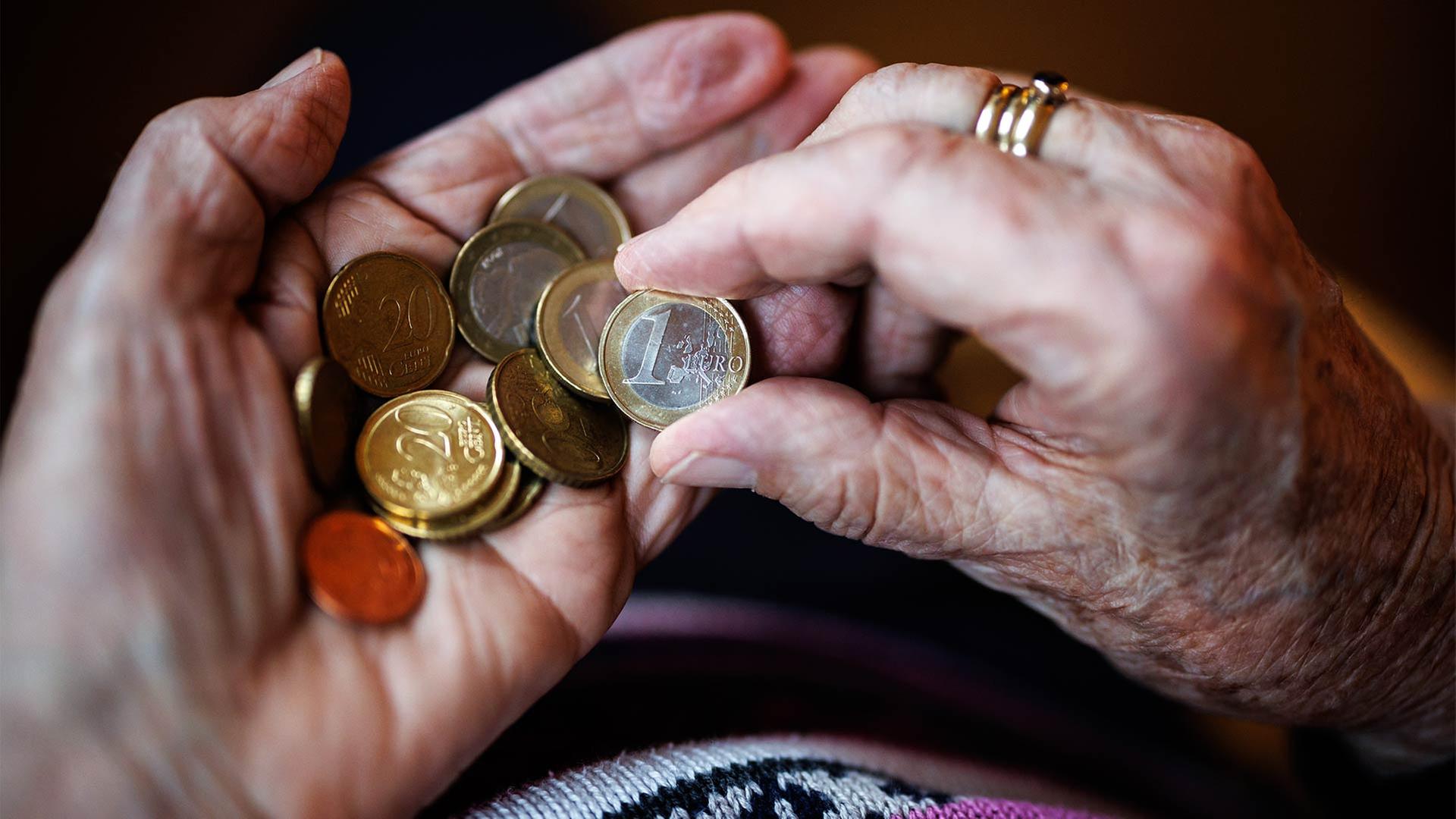 Eine alte Frau zählt in ihren Händen das Bargeld aus ihrem Portemonnaie ab. | picture alliance / dpa