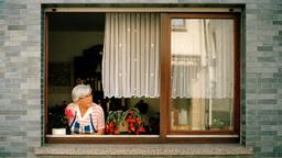 Ältere Frau schaut aus dem Fenster.