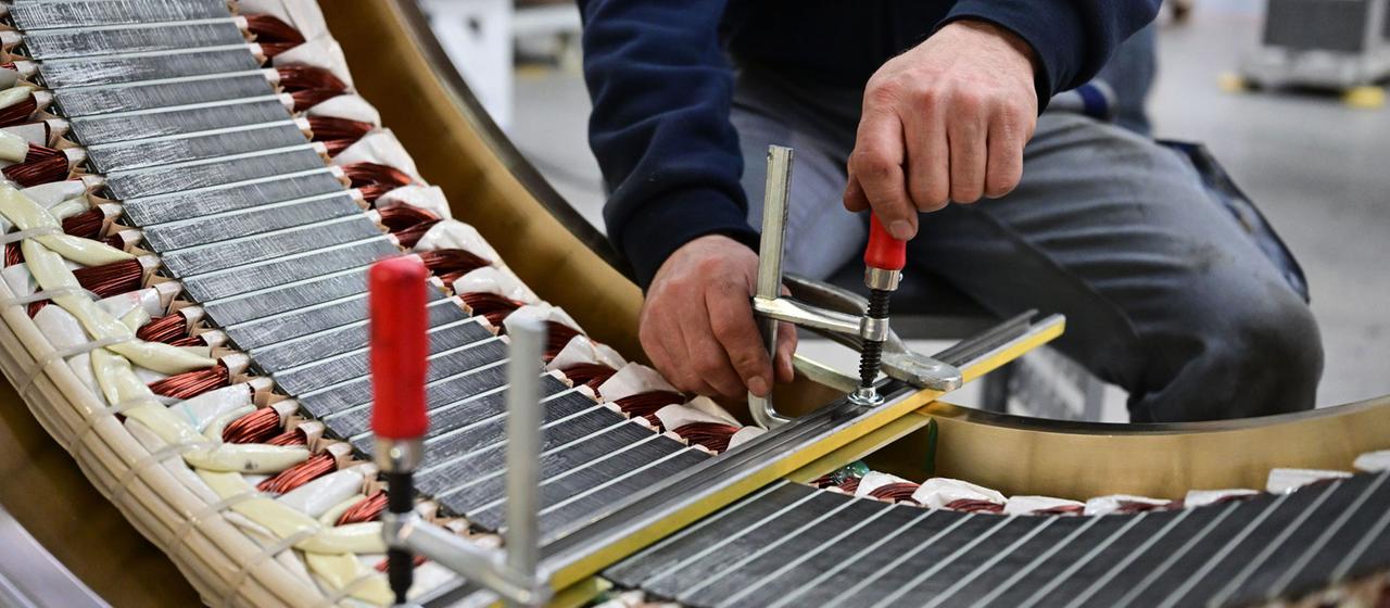 Ein Arbeiter arbeitet an einer Komponente einer Turbine für ein Wasserkraftwerk.