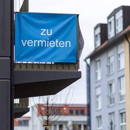 "Zu vermieten" steht auf einer Plane, die an einem Balkon-Geländer einer Neubau-Wohnung angebracht ist.