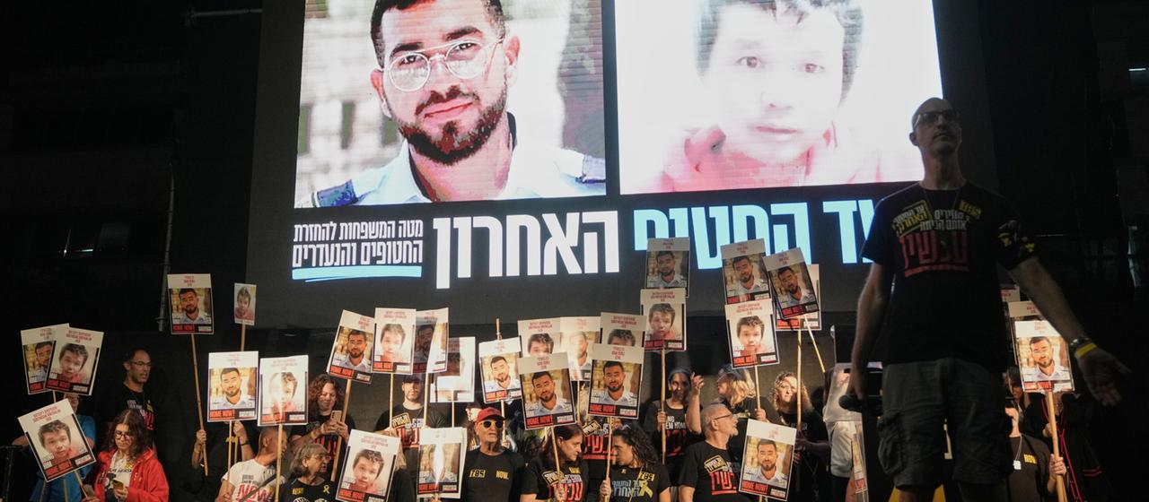 Menschen halten in Tel Aviv Fotos von noch zwei im Gazastreifen festgehaltenen toten Geiseln hoch.