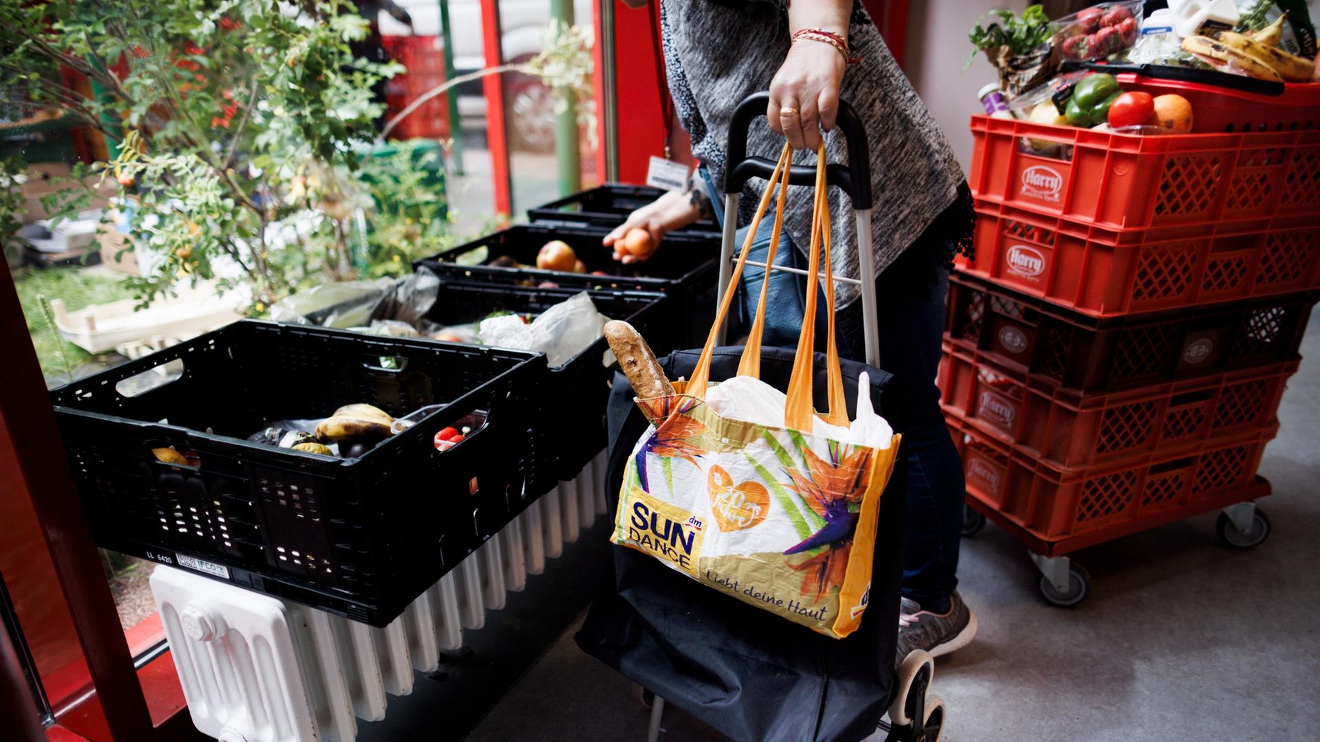 Eine Frau sammelt Obst aus einer Kiste in der Ausgabestelle Paul-Schneider-Haus der Berliner Tafel. | dpa