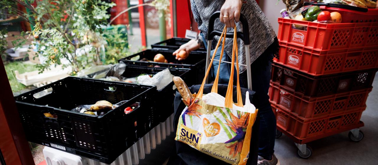 Eine Frau sammelt Obst aus einer Kiste in der Ausgabestelle Paul-Schneider-Haus der Berliner Tafel.