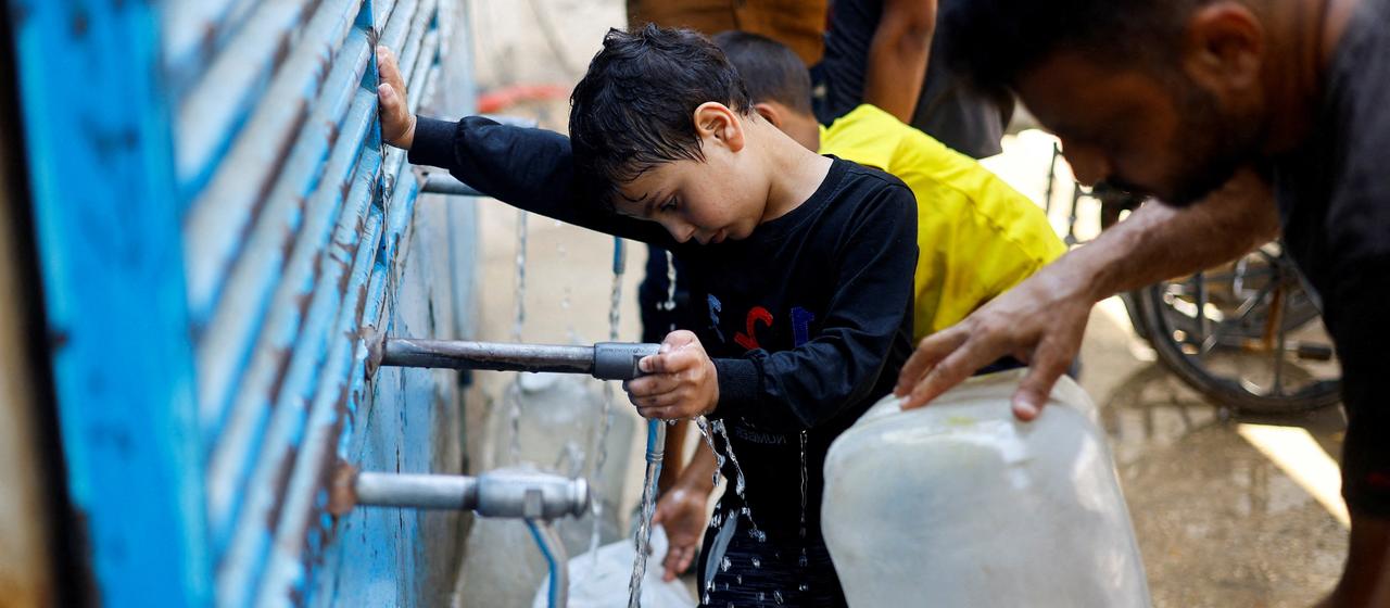 Palästinenser füllen an einer Wasserverteilungsstelle in Nuseirat im Zentrum des Gazastreifens Kanister mit Wasser.