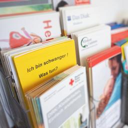 Broschüre einer Schwangerschaftsberatung stecken in einem Display.
