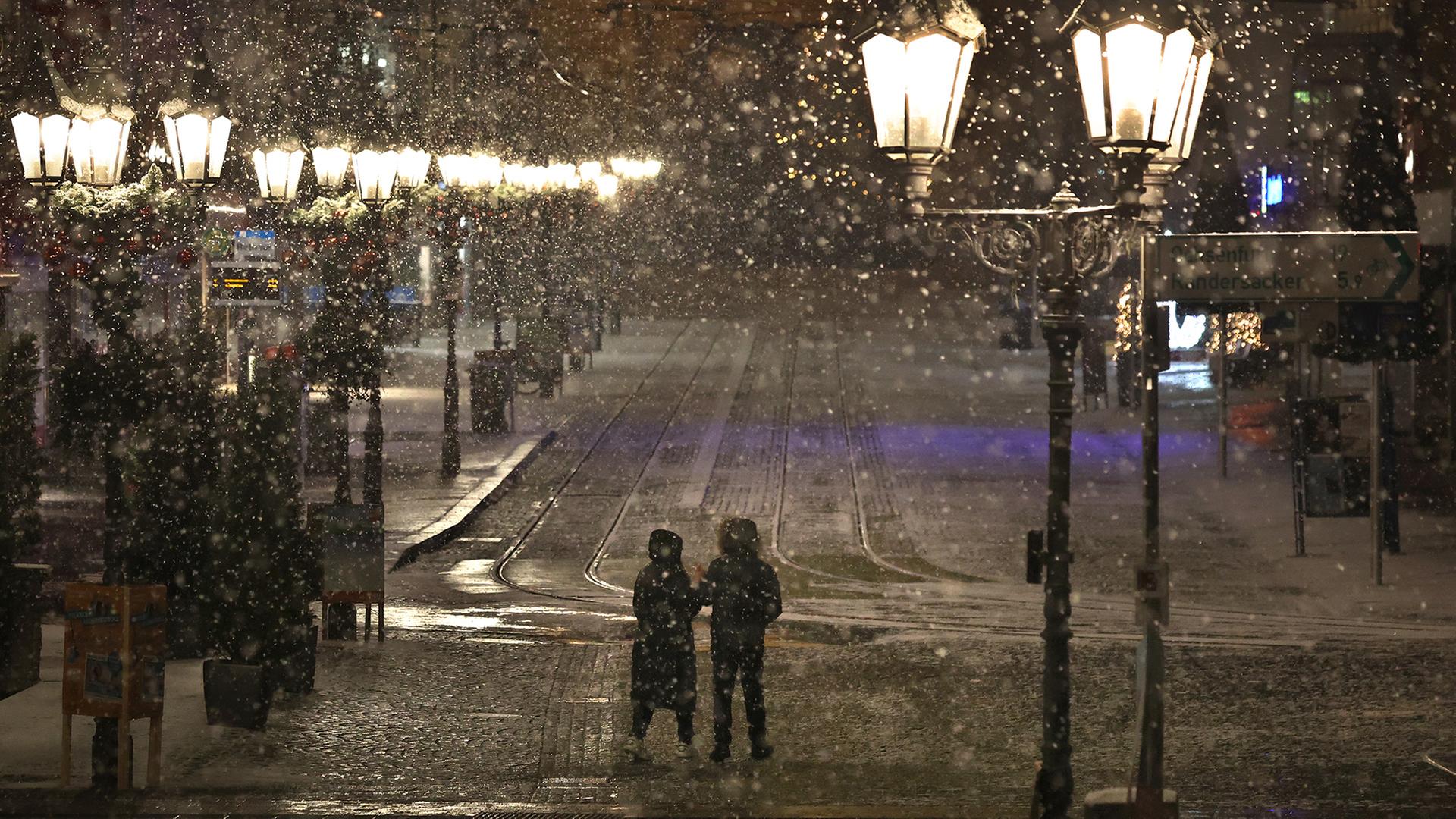 Ein Paar spaziert im Schneetreiben. (Archivbild) | dpa