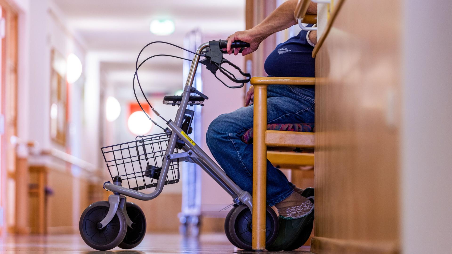 Ein Bewohner sitzt mit seinem Rollator auf einem Flur in einem Pflegeheim | Jens Büttner/dpa