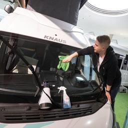 Ein Mann putzt am Vortag der Eröffnung der Urlaubsmesse Caravan Motor Touristik (CMT) die Windschutzscheibe eines Campervans.