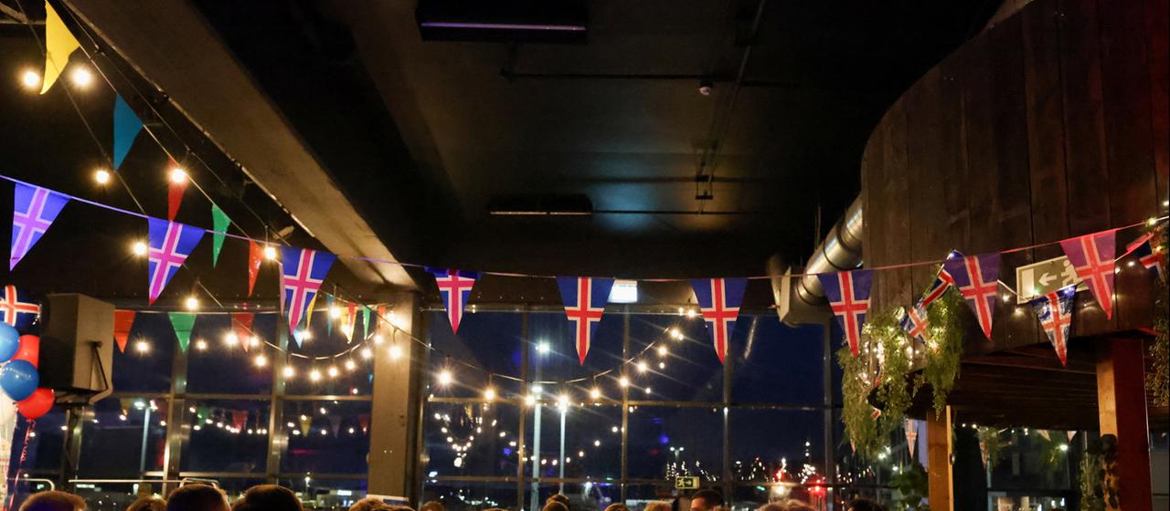 Ein Raum voller Menschen, über ihren Köpfen hängen Island-Flaggen.