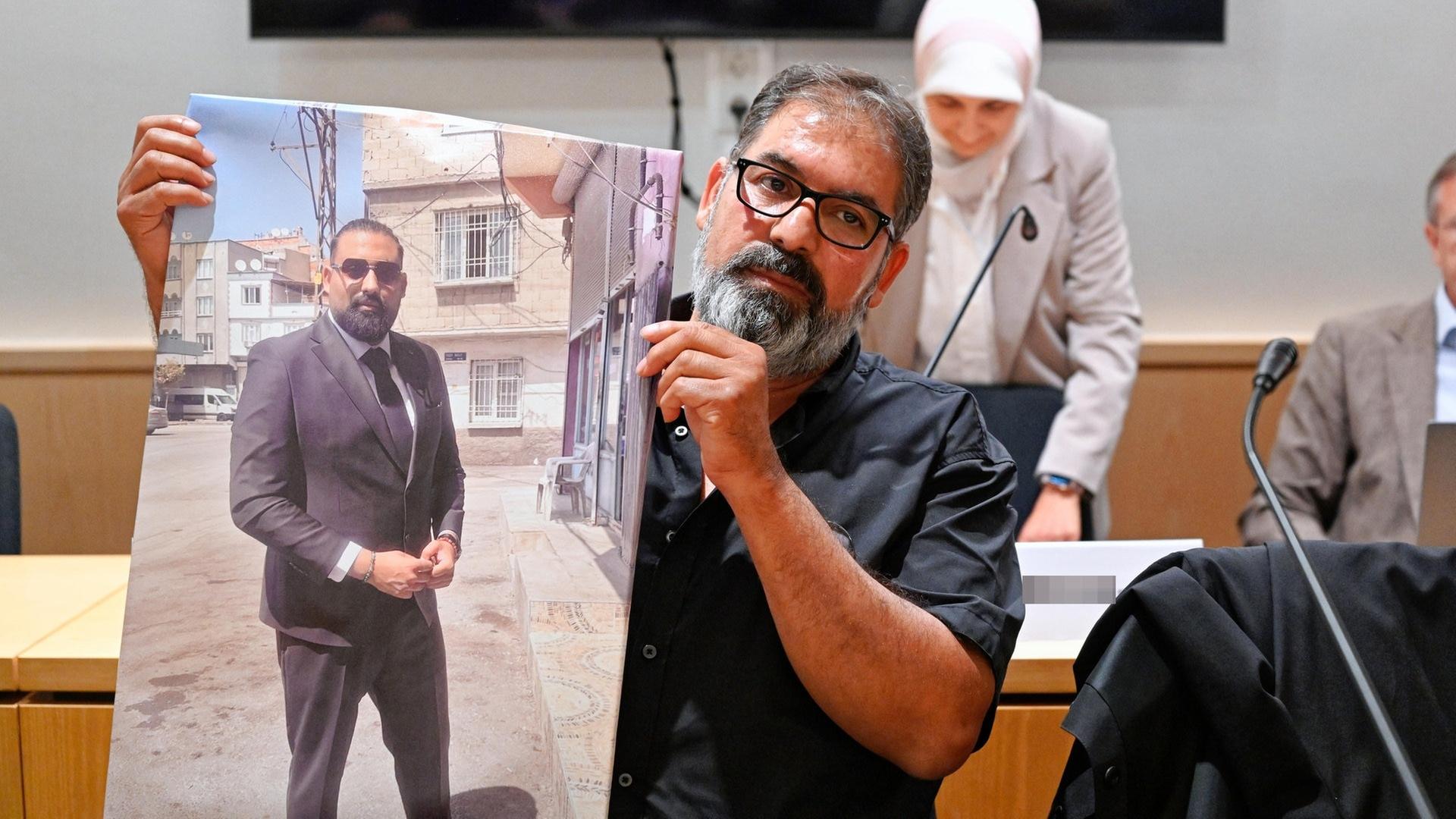 Erdal Calar, Vater des getÃ¶teten Zugbegleiters Serkan Calar, hÃ¤lt im Verhandlungssaal des Landgerichts ein Bild des Opfers in den HÃ¤nden. | picture-alliance / Reportdienste, picture alliance/dpa/dpa POOL | Uwe Anspach