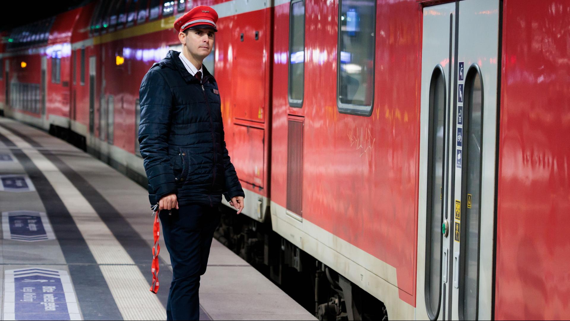 Ein Schaffner steht vor einem Zug. | dpa