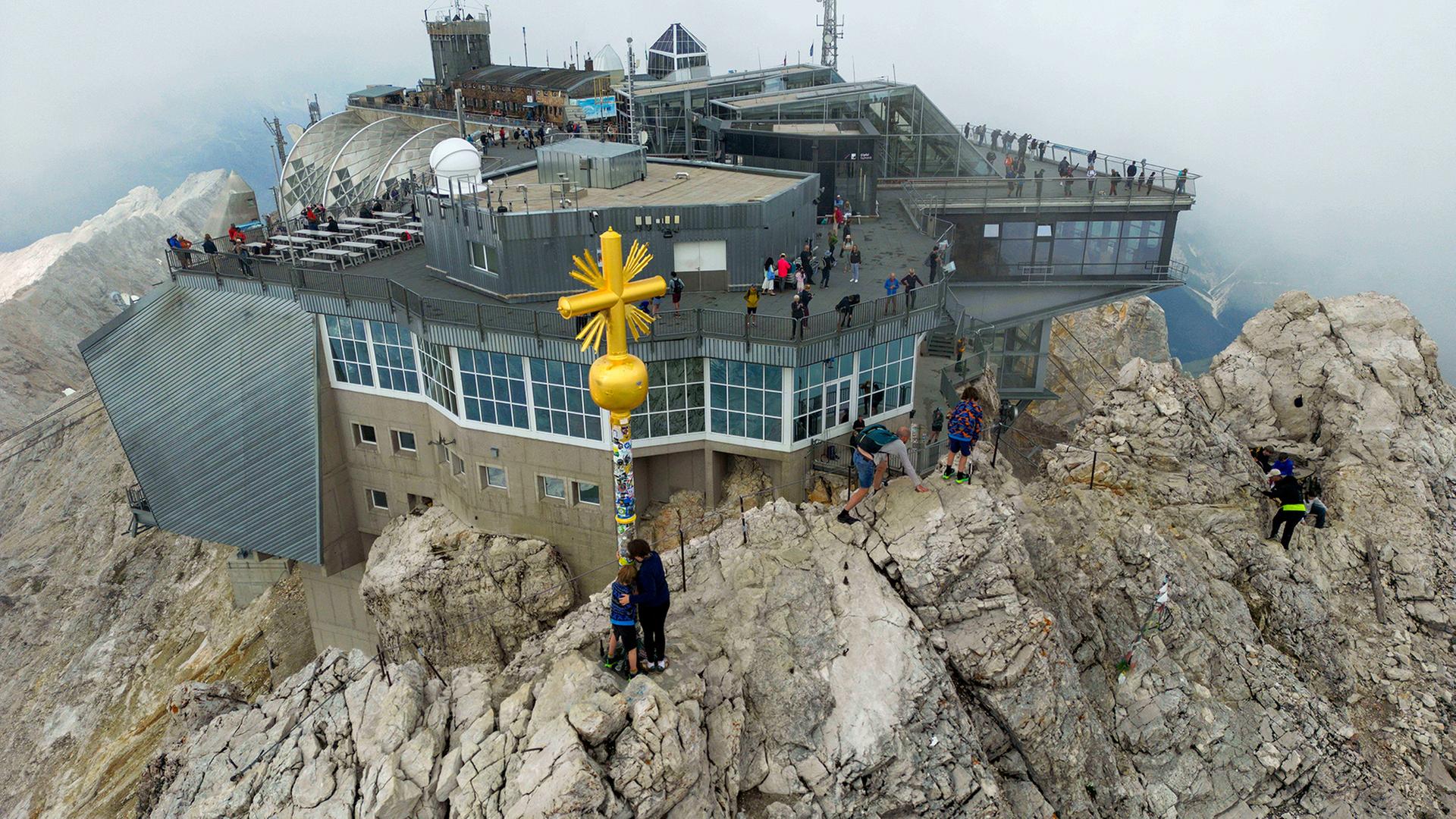 Wanderer am Gipfelkreuz auf der Zugspitze. | dpa