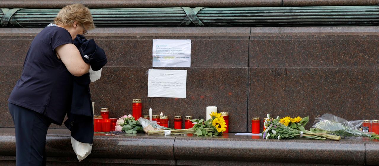 Eine Frau steht vor dem Gesundheitsministerium in Wien vor Blumen und Kerzen.